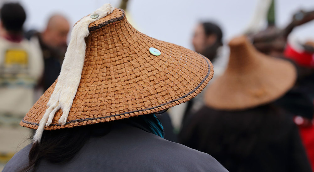 Cedar bark hat embellished with ermine pelt and abalone button.