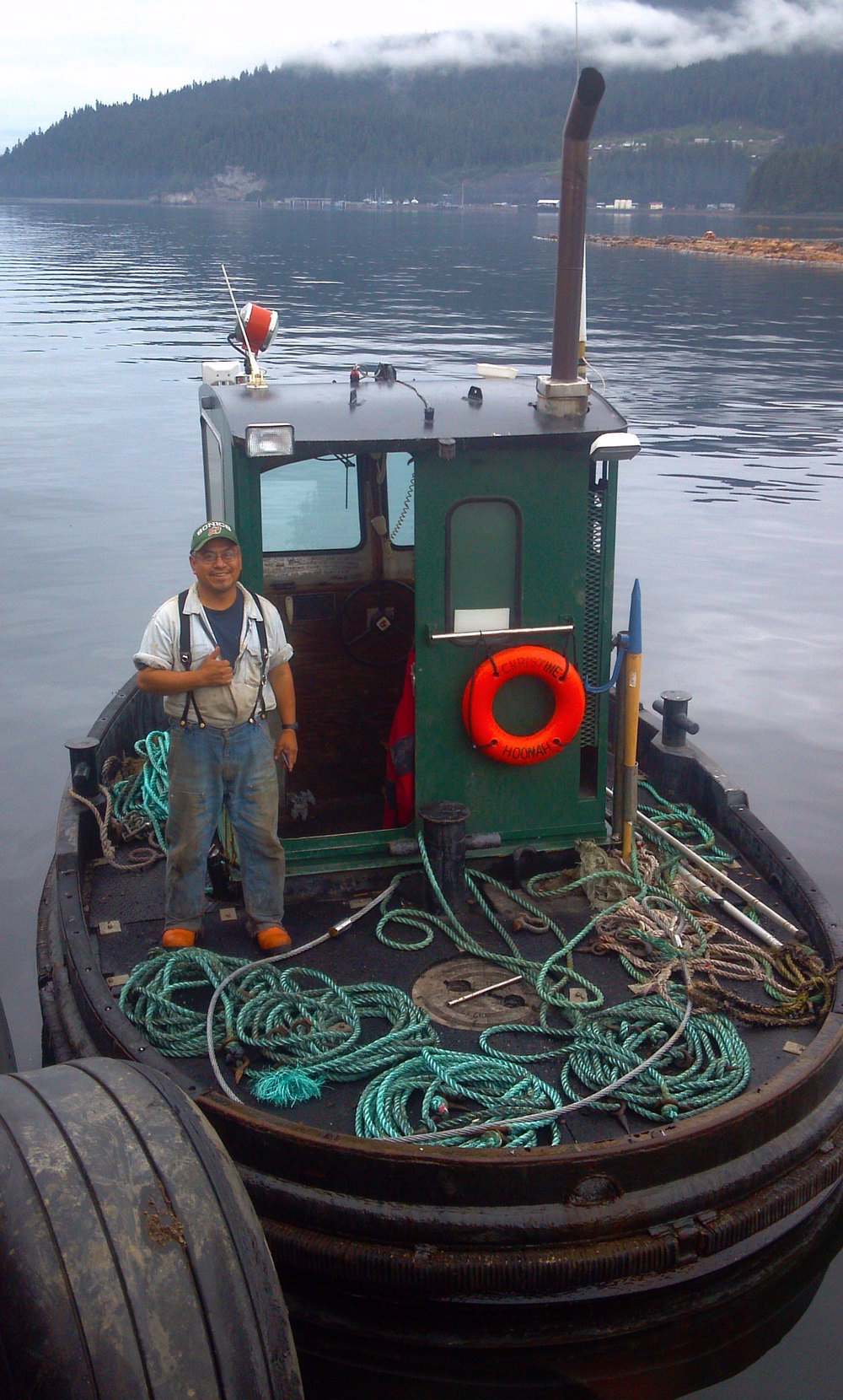 Skipper Jimmy Dalton on the "Christine". In the background is one of the log rafts he is building. Photo by Harold Medalen.