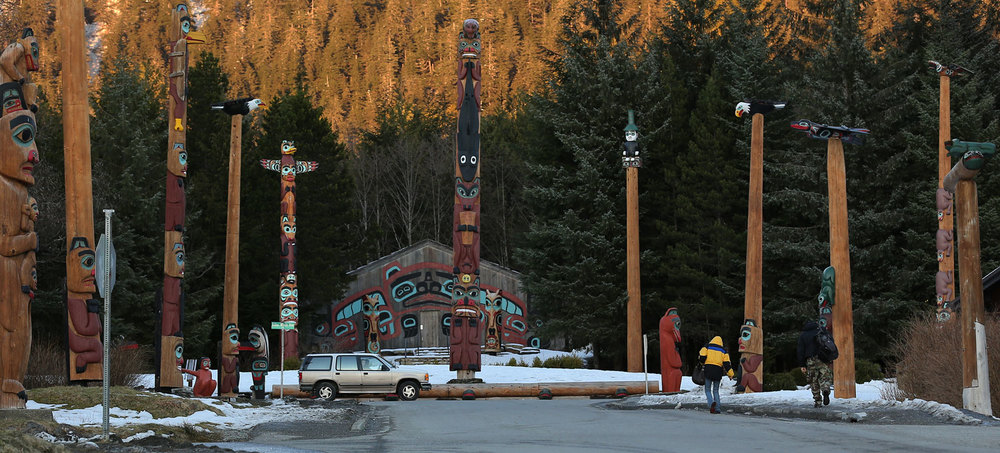 Residents walk home surrounded by totem poles on a late winter day in Saxman, Alaska.