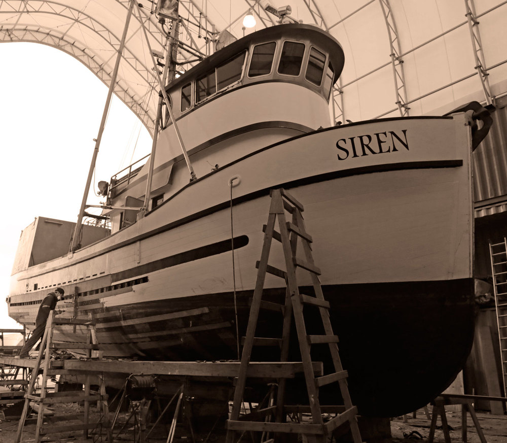 Mike File working on replacing planks replanking fishing boat FV Siren built in 1919 Petersburg Wrangell Alaska Marine Service Center boatyard shipyard